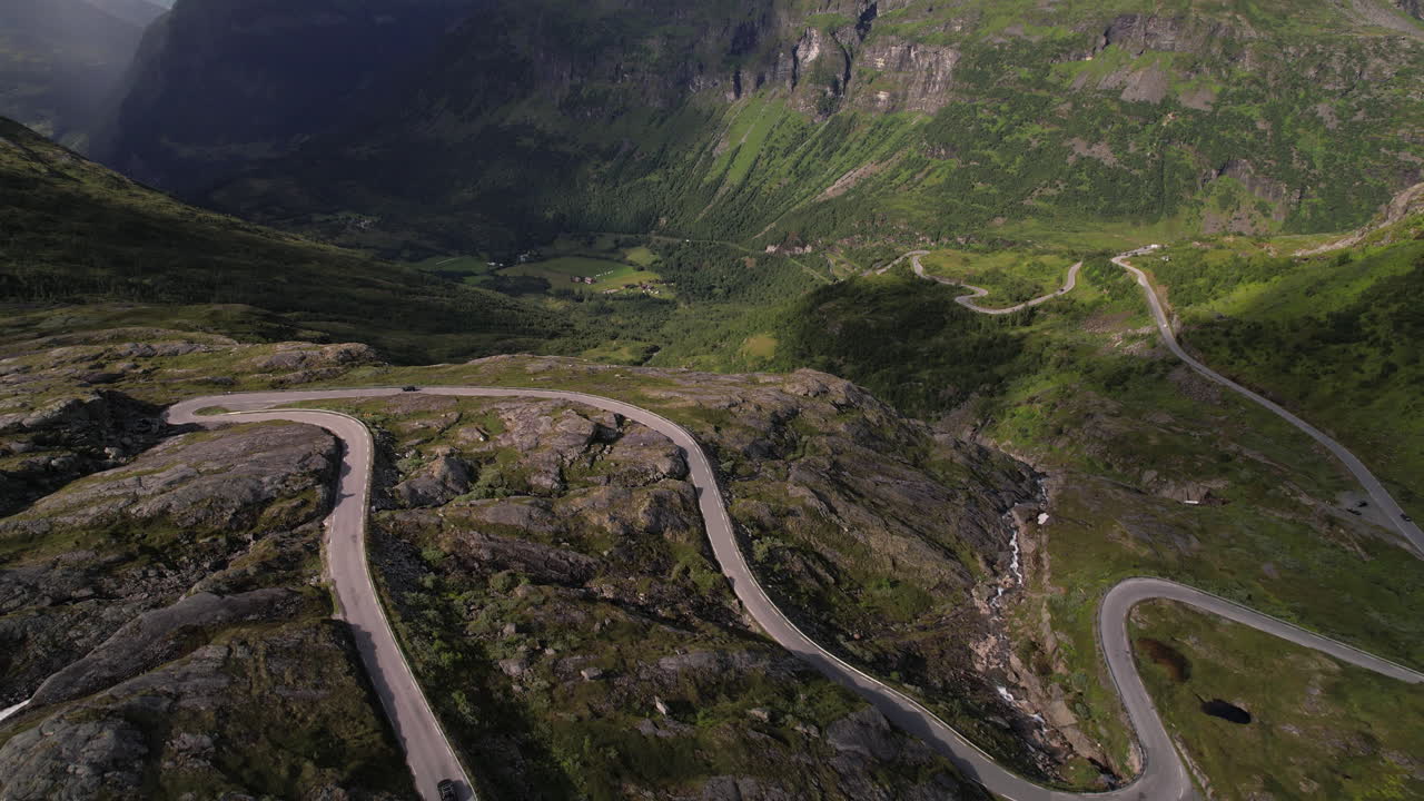 vista aérea de automóviles que conducen a lo largo de un paso de montaña en una cumbre rocosa en noruega, carretera a geiranger y geirangerfjord