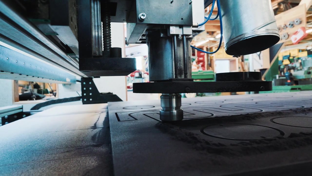 Drammatica prospettiva dal basso di una testa CNC che si muove su un pannello lavorato durante il taglio.
