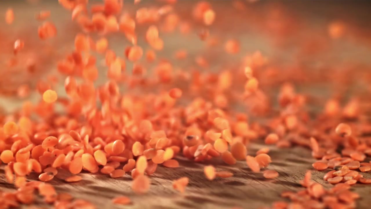 Close Up of Red Lentils Falling onto a Rustic Wooden Surface