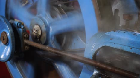 blue industrial machine moved by a steam engine releasing working fluid steam and rotating in a mechanical manner