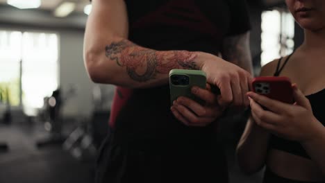 hombre y mujer mirando sus teléfonos en el gimnasio