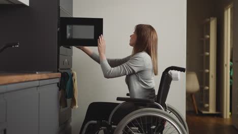 woman with disability takes out plate of food from microwave