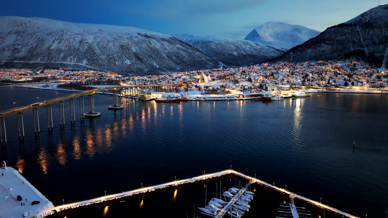 Winter night aerial view over Tromsoysundet of snowy Tromso city and bridge