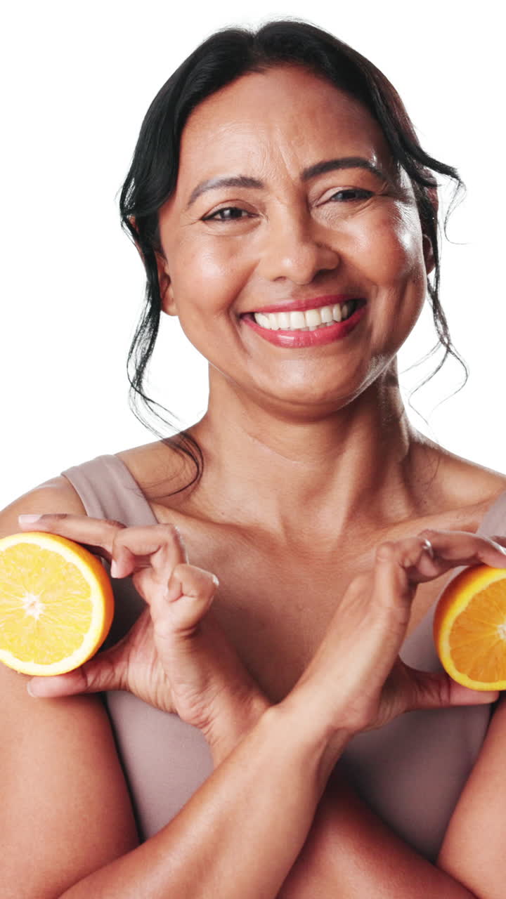 Donna sorridente che tiene metà di arance a forma di cuore