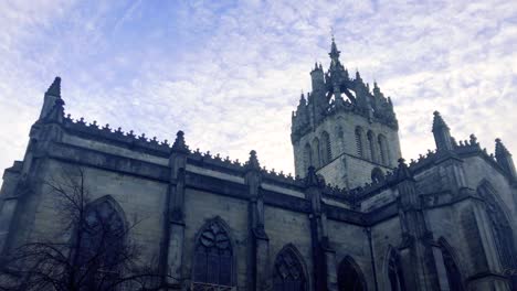 Slow-moving-clouds-moving-above-a-church-and-statue,-on-a-cold-and-cloudy-day-in-Scotland