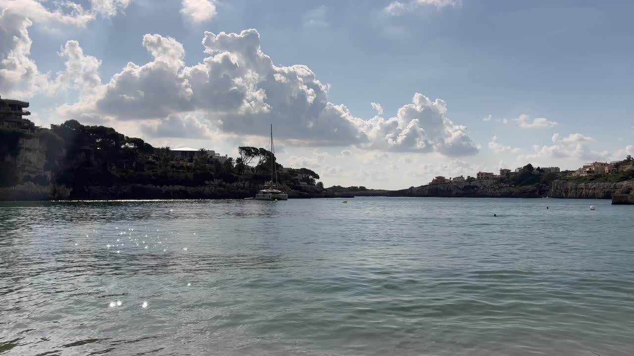 스페인 마요르카 포르토 크리스토의 바위 해안선과 절벽 근처 잔잔한 물에 정박된 돛단배