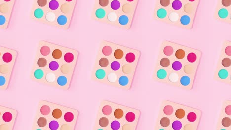 beauty pattern made of colorful eye shadow palettes rotate on bright pink background. stop motion