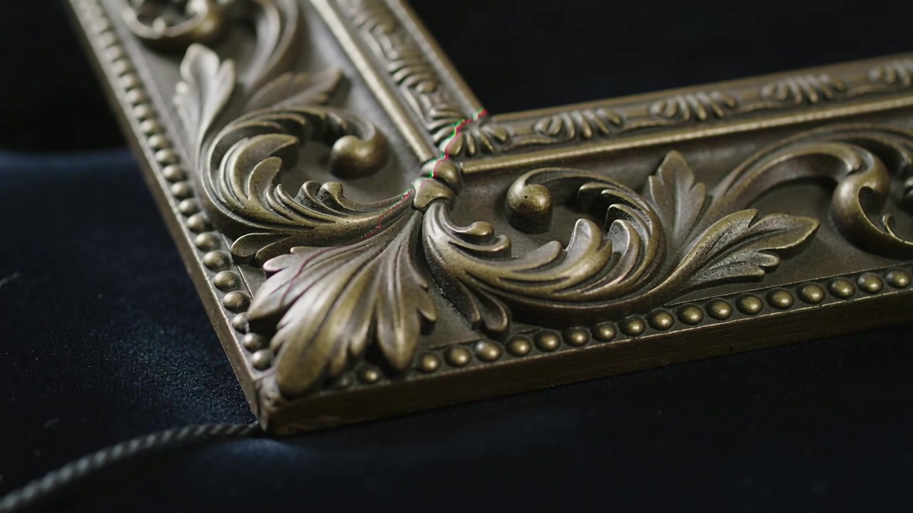 Moving camera making color fringe while showing gilded frame corner on velvet, braided cord detail
