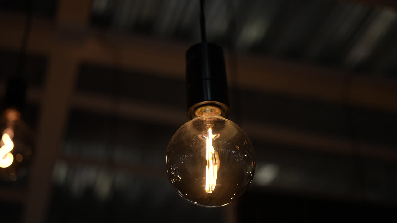 Illuminated light bulb hanging from a string of lights on the deck or porch - decorative glowing ambiance