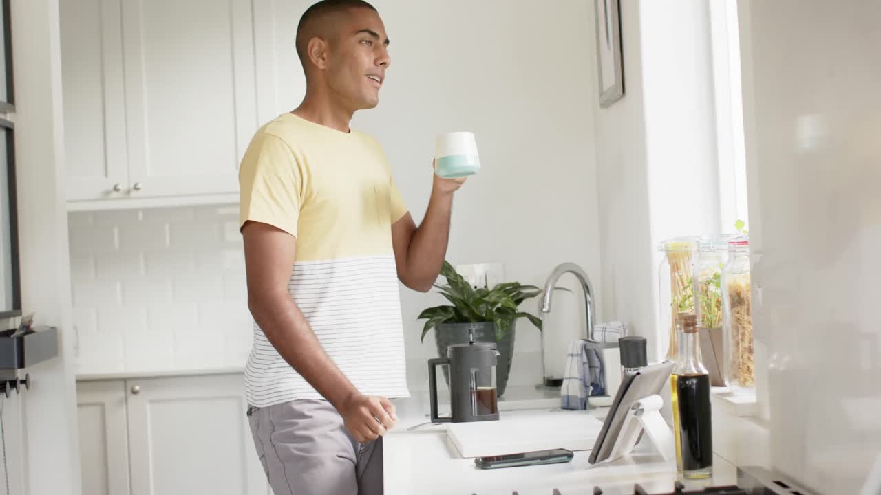 hombre biracial feliz haciendo café en una cocina brillante, cámara lenta