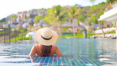 espalda de una mujer hermosa dentro del agua de la piscina en un resort tropical en miami, portátil en cámara lenta