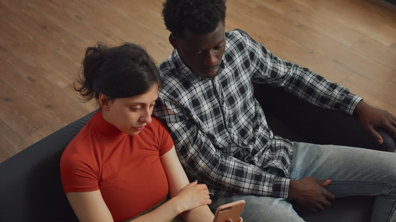 Close up of interracial couple looking at smartphone