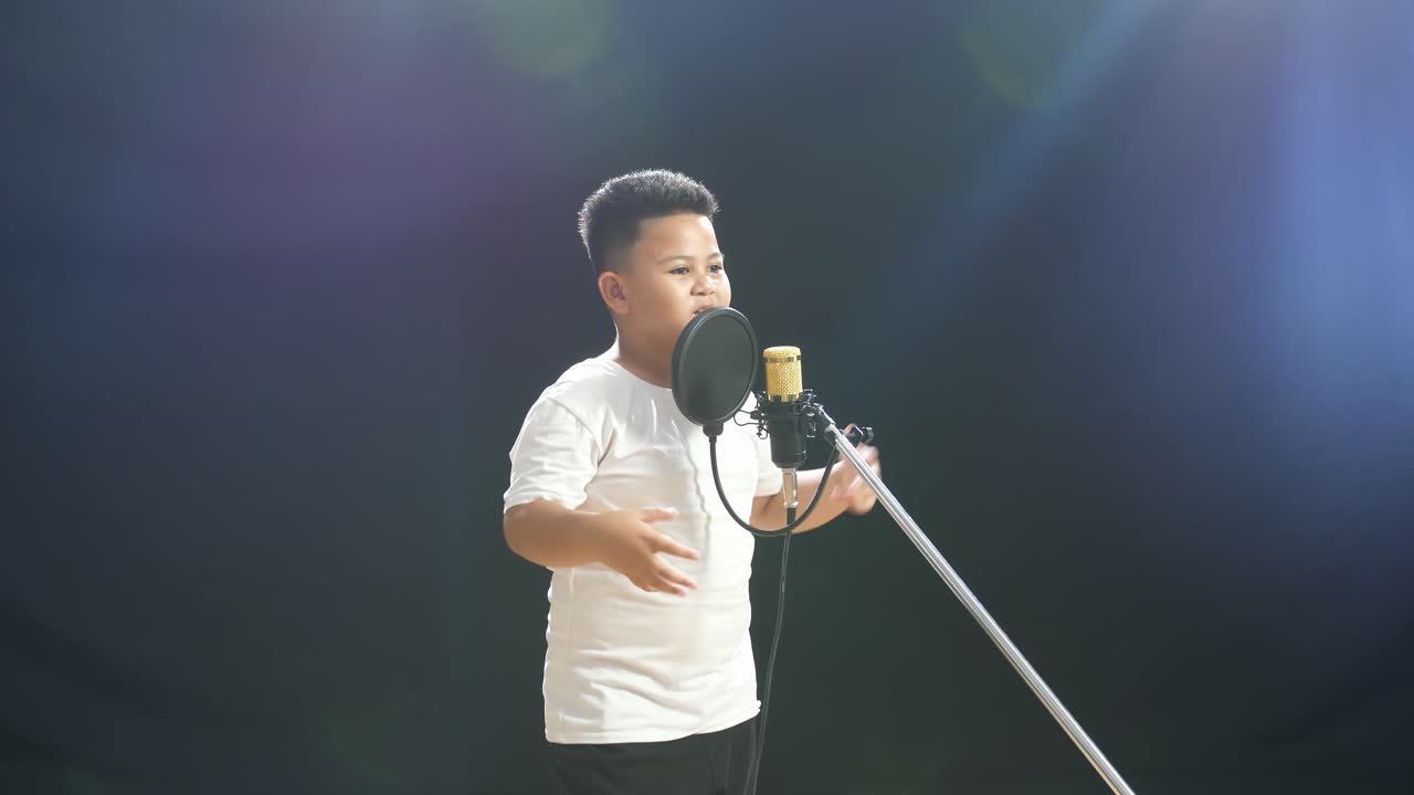 어린 소년 이 마이크 로 노래 하고 있다