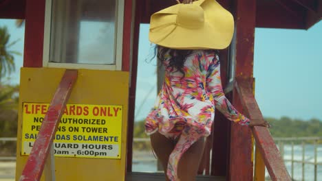 una joven sube los escalones de una cabina de salvavidas en un bikini sexy antes de darse la vuelta