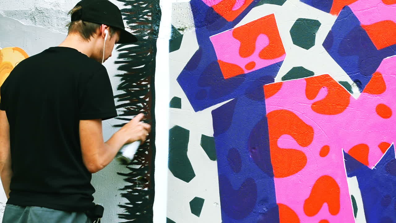 O artista desenha grafite em uma cerca. Desenho abstrato