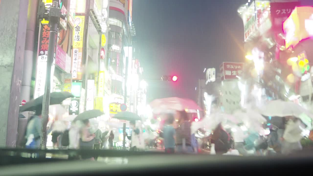 비가 내리는 도쿄 신주쿠의 교차로를 건너는 사람들