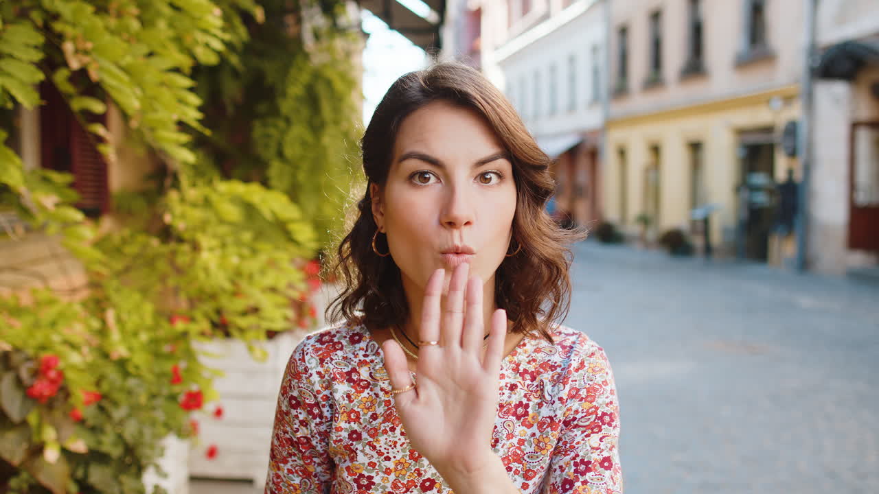 Young woman presses finger to lips makes silence hush sign do not tells gossip secret quiet in city