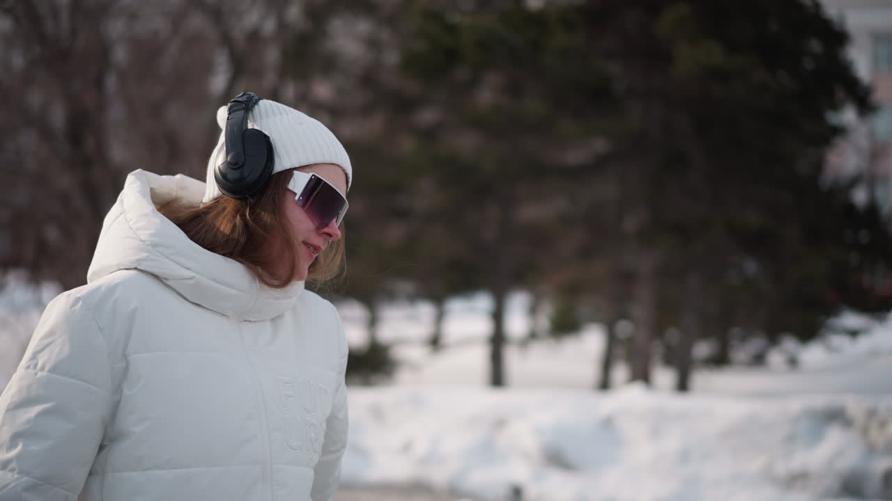 Breezy snowy environment as girl turns in dance moves on icy urban pavement with wind blowing through trees and drifts visible in background capturing fluid motion and joyful expression