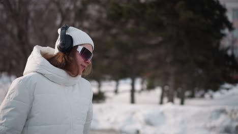 breezy snowy environment as girl turns in dance moves on icy urban pavement with wind blowing through trees and drifts visible in background capturing fluid motion and joyful expression