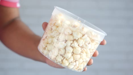 hand holding a container of popcorn