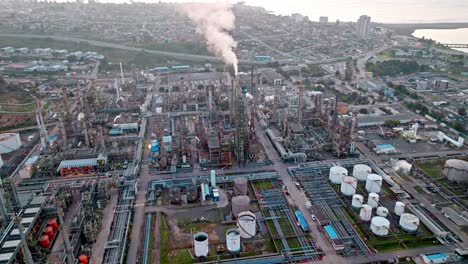 Bird's-eye-view-dolly-in-of-ENAP-Aconcagua-refinery-in-Concon,-Chile-with-the-sunset-in-the-background