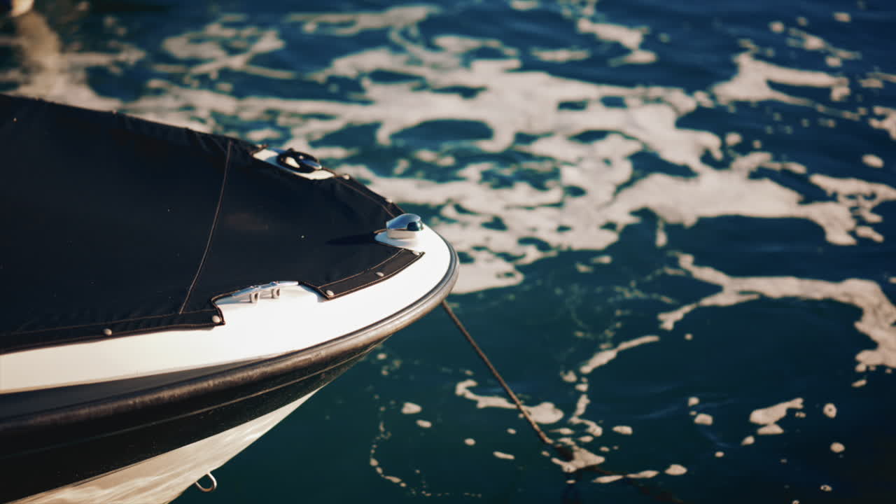 Close up of a boat's bow surrounded by sea foam in sunlight