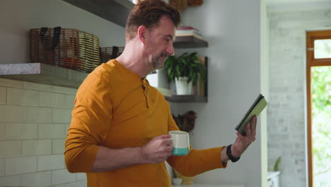 smiling man holding tablet and coffee mug at home during video call
