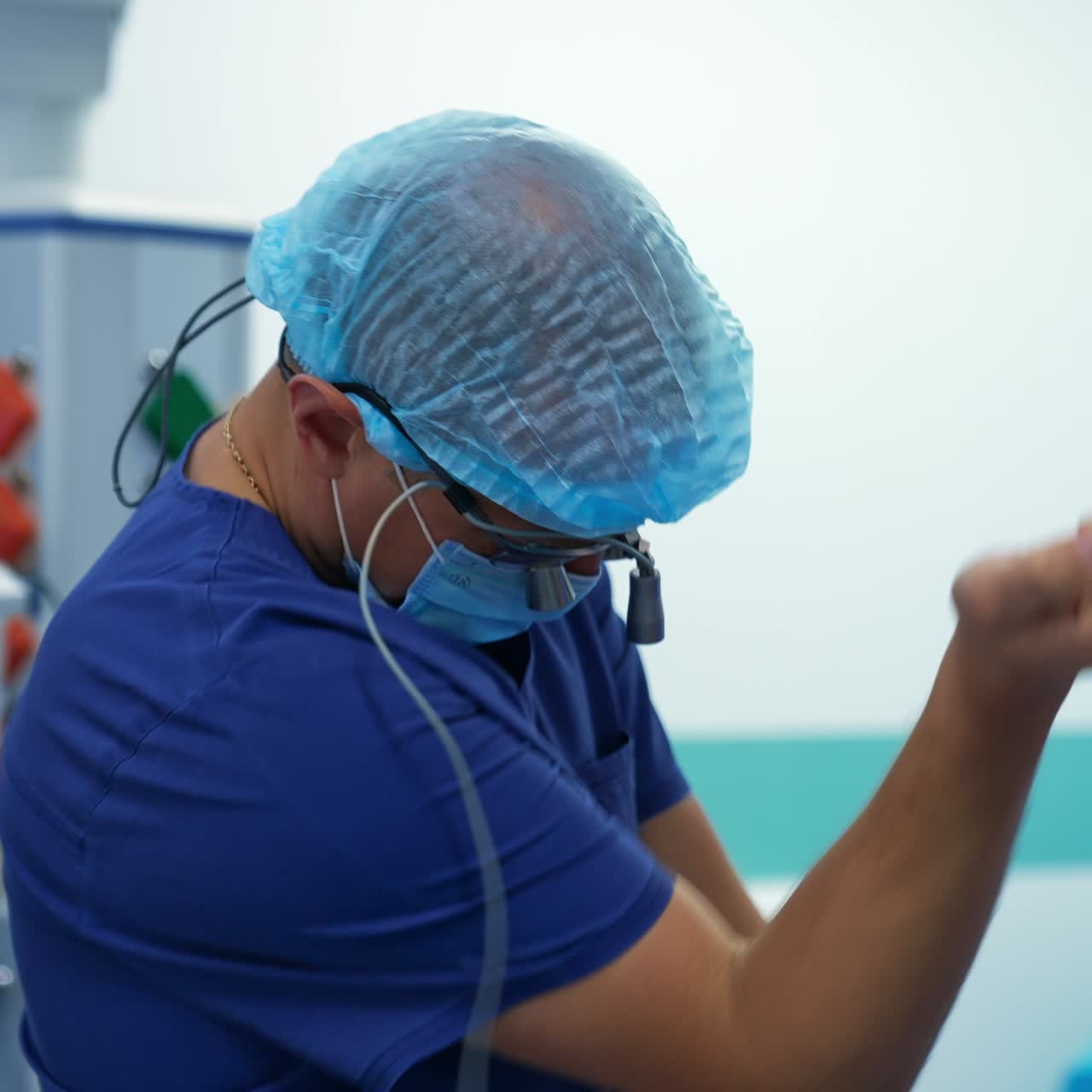 Putting on the equipment device on the head. Male surgeon preparing for operation in modern surgery theatre