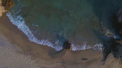 Slomotion-aerial-drone-clip-moving-over-a-sandy-beach-and-a-rock-formation-in-Kavala,-Macedonia,-Greece