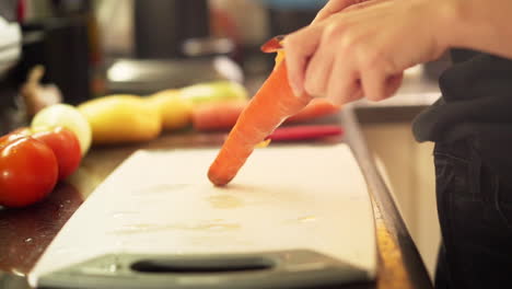 manos femeninas pelando zanahorias en la cocina a cámara lenta