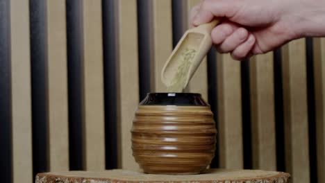 pouring yerba mate into a gourd with a wooden spoon in a wooden scenery