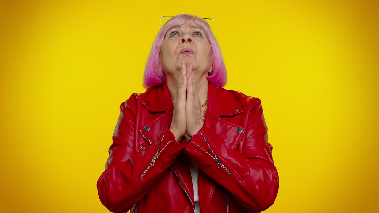 Mature old woman praying to God making wish asking with hopeful imploring expression begging apology