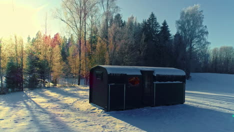 puesta de sol dorada y un remolque de cabaña y sauna en un campo nevado - retiro aéreo revela