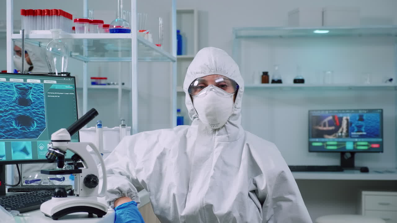 실험실 에서 카메라 를 보고 옷 을 입은 피곤 한 미생물학자