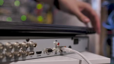 a technician inside the server room, inserting a cable into the lan port of a computer or router