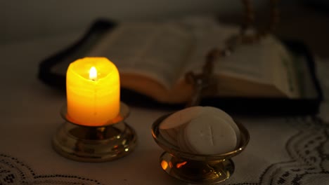 communion hosts lit candle and holy bible