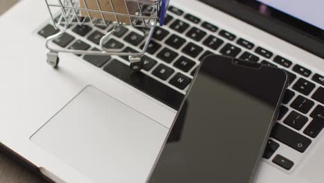 cajas en el carrito de compras y teléfono inteligente en el teclado de la computadora portátil