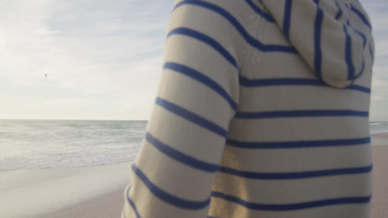 Rückansicht eines hispanischen Paares, das am Strand rennt und Spaß hat