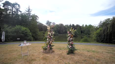 escenario de ceremonia de boda boho al aire libre junto al lago, sillas rústicas y arco de boda