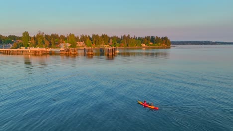 Aerial-drone-view-of-two-people-young-couple-paddling-a-kayak-back-to-shore-at-sunrise-near-seattle-washington