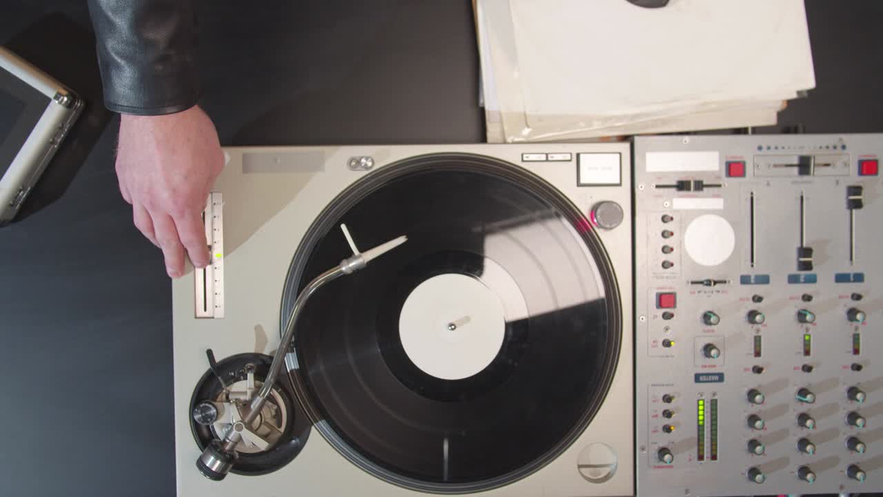 dj는 턴테이블의 버튼을 누르고 슬라이더를 움직입니다.