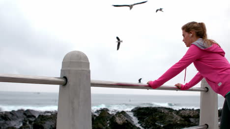 fit woman stretching leg on railing