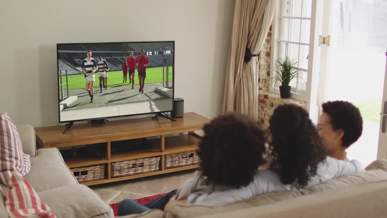 Famiglia felice seduta a casa insieme che guarda una partita di rugby in TV