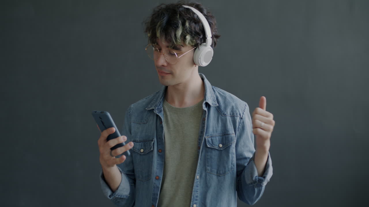 Young Man Dancing to Music on Smartphone