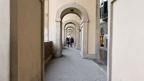 gente caminando bajo los arcos históricos del ponte vecchio