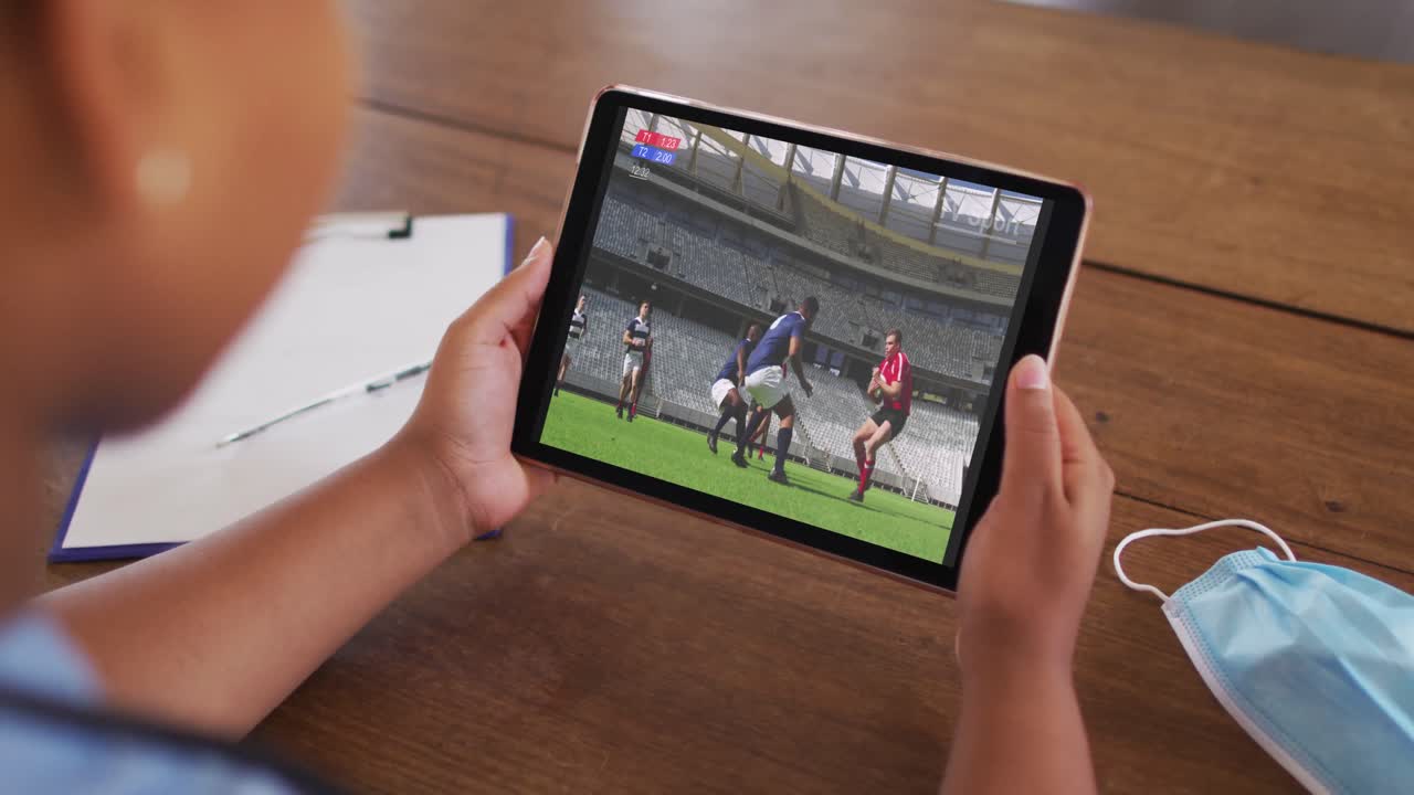 태블릿에서 럭비 경기를 시청하는 집에서 소파에있는 여성의 복합