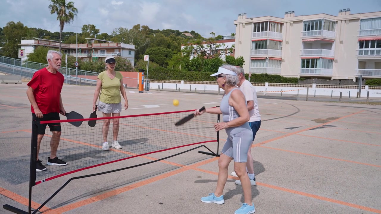 Adultos mayores activos jugando pickleball juntos en un día soleado.