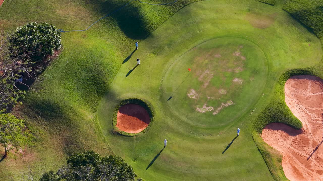 Ripresa aerea dall'alto mostra golfisti e golf cart che si muovono su un lussureggiante campo da golf