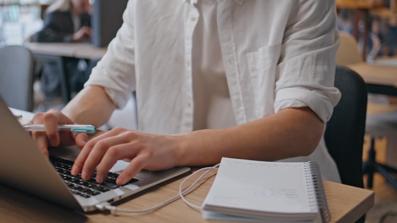 Man hands taking notes at office desk closeup. Programmer typing laptop keyboard