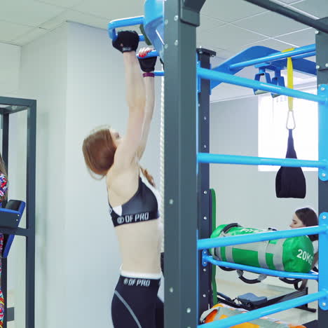 strong woman with long hair tightening on the bar in the sport club. active women doing workouts on modern simulators indoors on the light gym background.